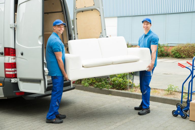 movers in blue uniform carrying a sofa