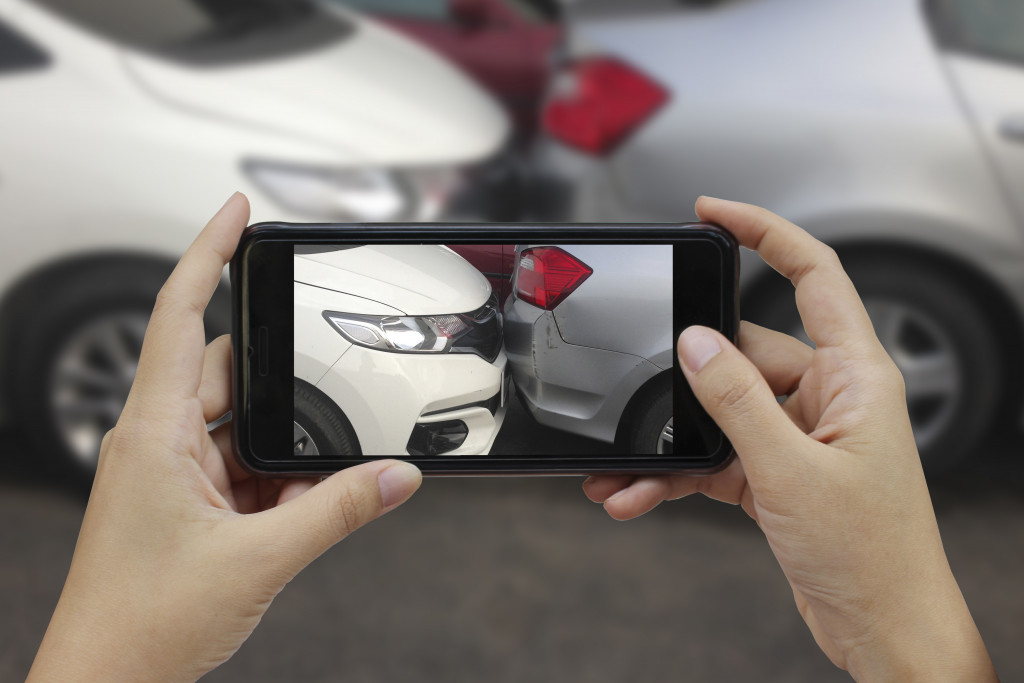 Someone taking a picture of two cars colliding using a touchscreen phone