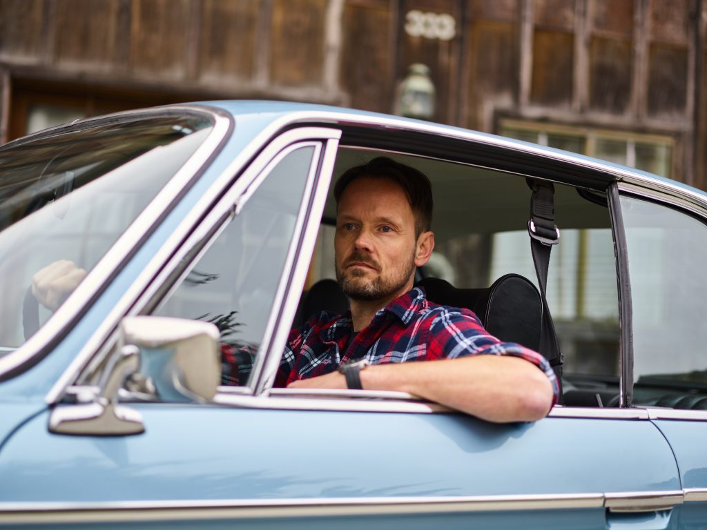 Thoughtful man driving car near old city house